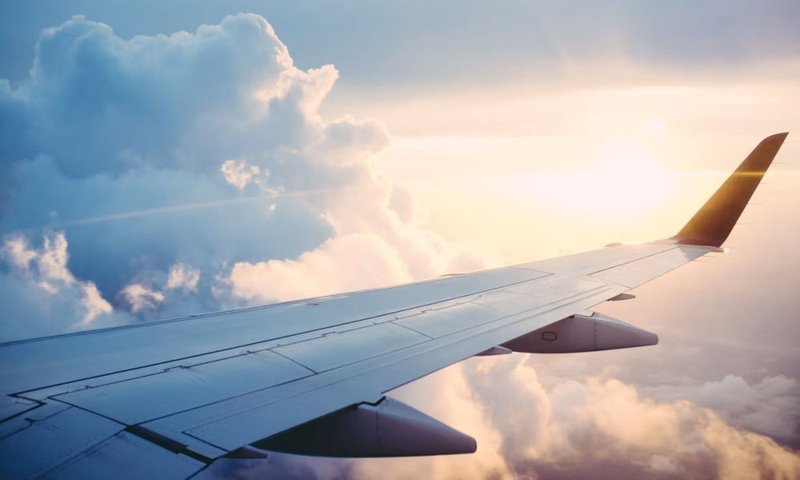 Airplane wing above clouds during travel