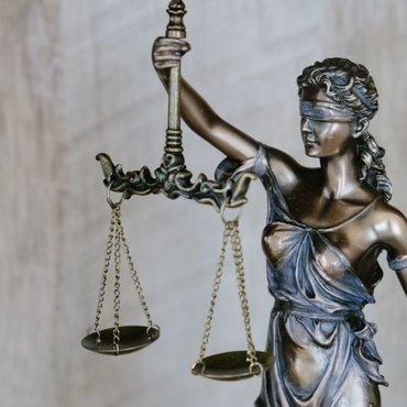 Brass scales of justice beside stacked law books
