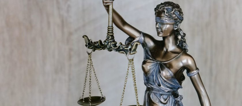 Brass scales of justice beside stacked law books