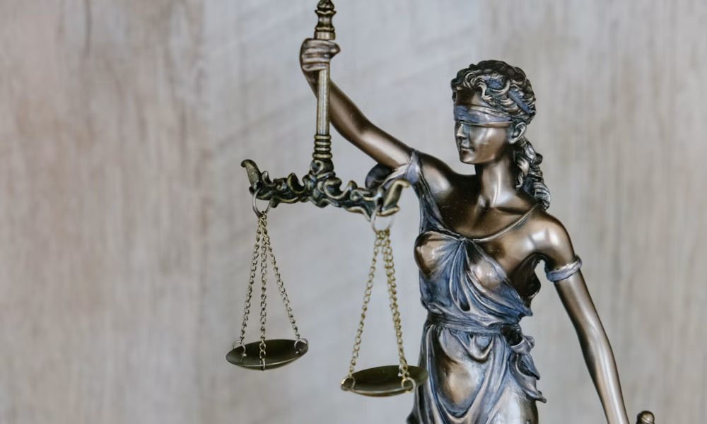 Brass scales of justice beside stacked law books