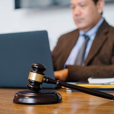 Judge’s gavel on a desk with a lawyer working on a laptop in the background