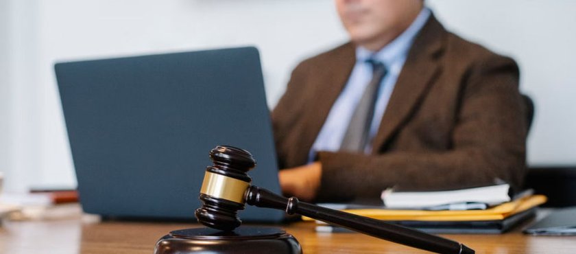 Judge’s gavel on a desk with a lawyer working on a laptop in the background
