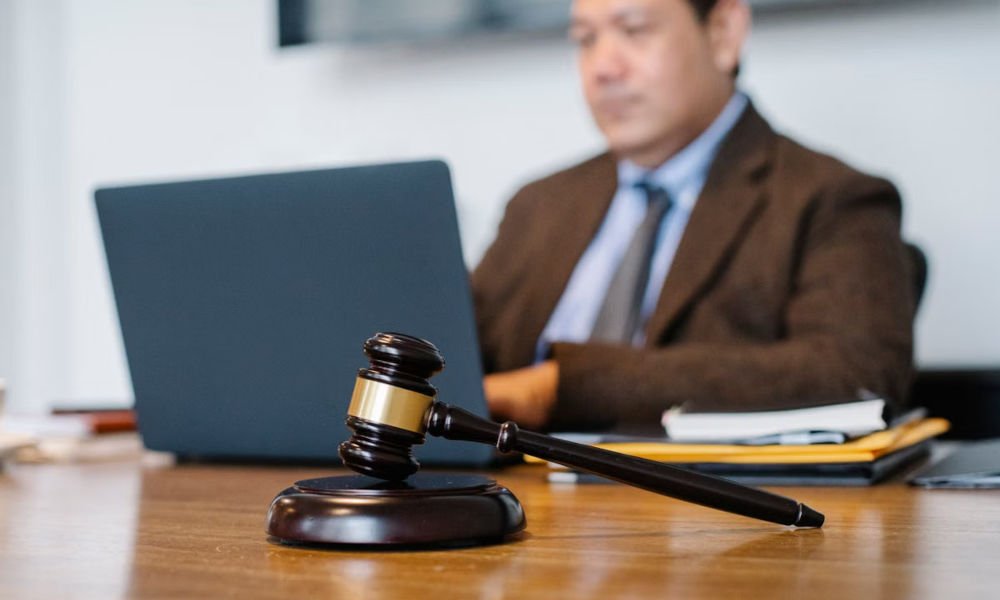 Judge’s gavel on a desk with a lawyer working on a laptop in the background