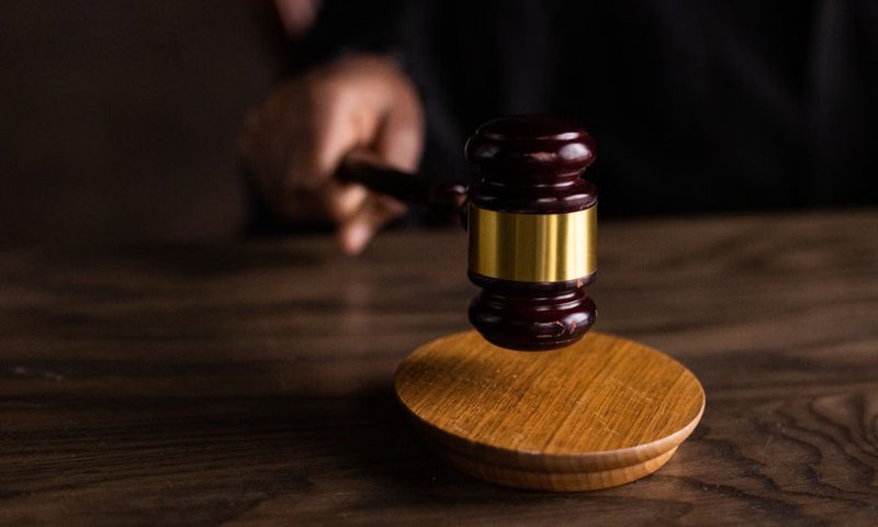 Judge’s wooden gavel hovering above a sound block in a courtroom setting