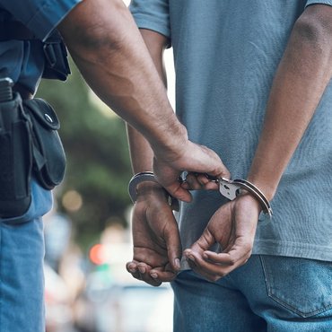 Handcuffs held by a police officer representing criminal conspiracy charges in Canada