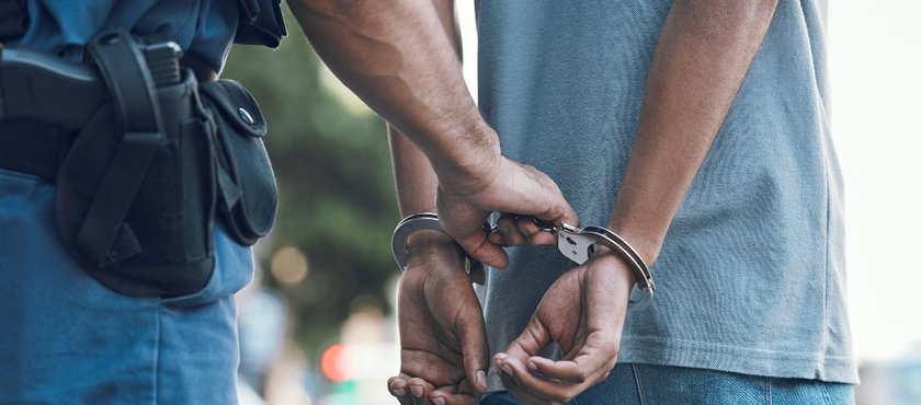 Handcuffs held by a police officer representing criminal conspiracy charges in Canada