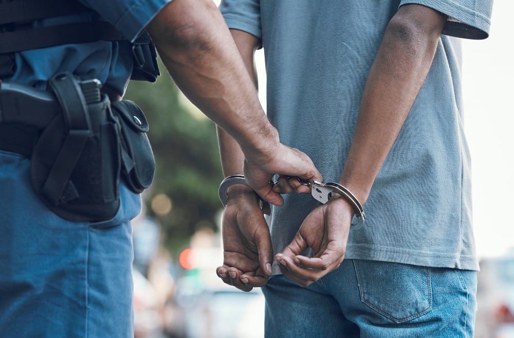 Handcuffs held by a police officer representing criminal conspiracy charges in Canada