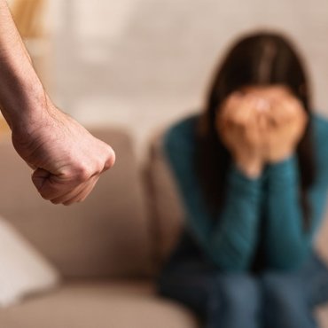 Man threatening his partner with a raised fist, illustrating how domestic assault charges are treated seriously under Ontario’s mandatory prosecution policy.