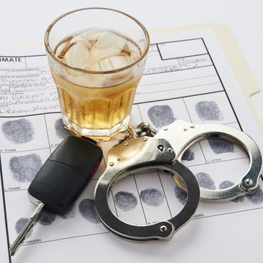 Conceptual image showing handcuffs, car keys, and alcohol, illustrating how DUI charges may affect employment and legal status in Ontario.