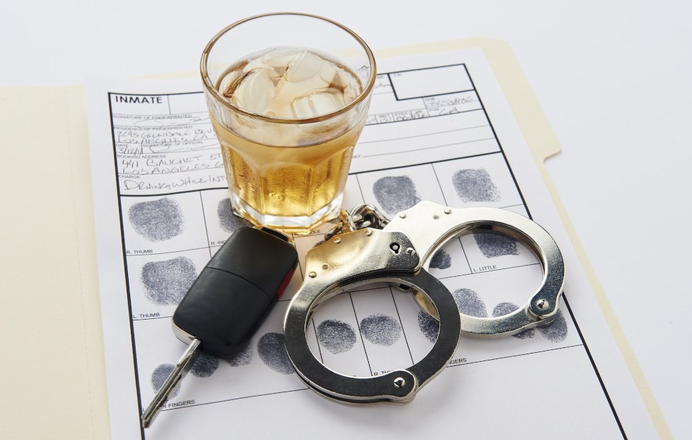 Conceptual image showing handcuffs, car keys, and alcohol, illustrating how DUI charges may affect employment and legal status in Ontario.