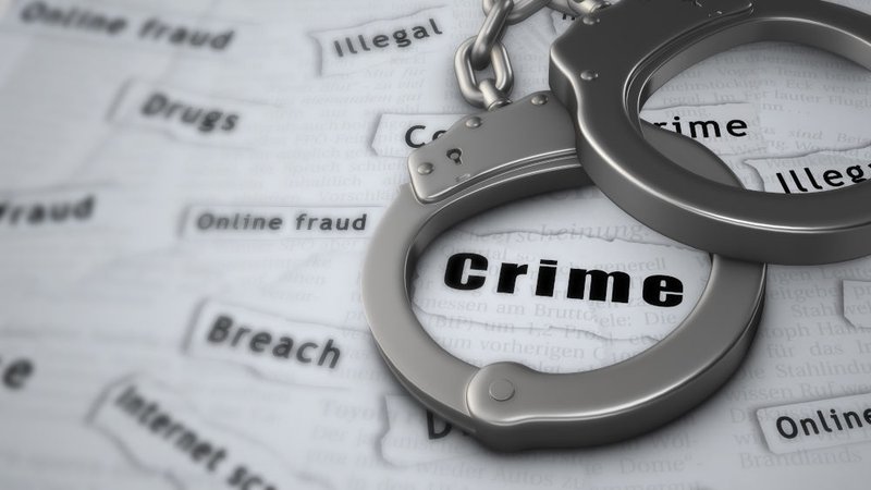 Handcuffs resting on a newspaper with a highlighted crime headline, symbolizing potential criminal charges and imprisonment for defamatory libel under Canadian law.