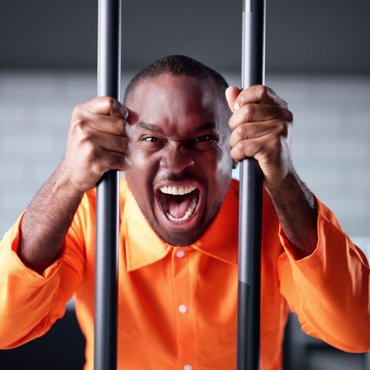 Insanity Defence in Canada: NCRMD and Criminal Responsibility Explained Alt: Man in an orange prison uniform behind bars, illustrating how NCRMD (Not Criminally Responsible on Account of Mental Disorder) is a legal finding that can still result in detenti