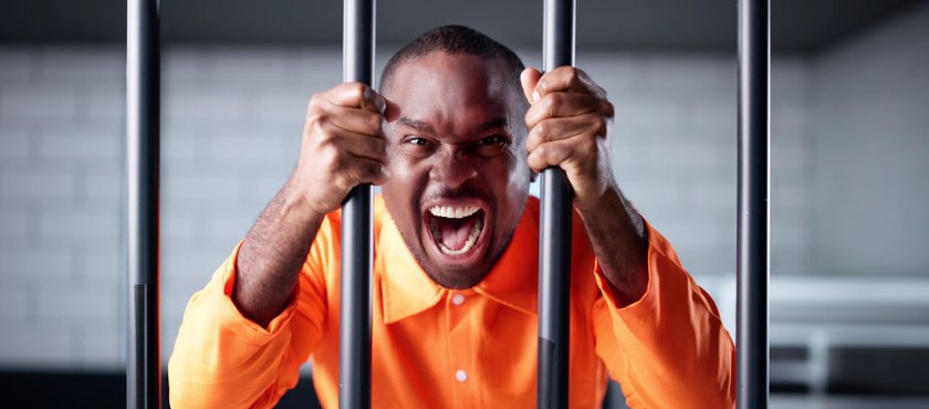 Insanity Defence in Canada: NCRMD and Criminal Responsibility Explained Alt: Man in an orange prison uniform behind bars, illustrating how NCRMD (Not Criminally Responsible on Account of Mental Disorder) is a legal finding that can still result in detenti