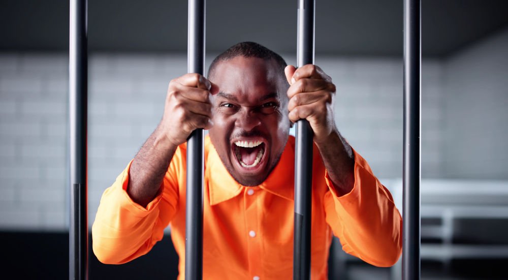 Insanity Defence in Canada: NCRMD and Criminal Responsibility Explained Alt: Man in an orange prison uniform behind bars, illustrating how NCRMD (Not Criminally Responsible on Account of Mental Disorder) is a legal finding that can still result in detenti
