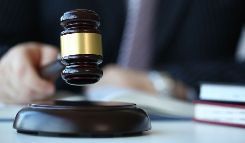 Judge holding a gavel in court, symbolizing judicial discretion to refuse adjournments, grant no-case motions, or dismiss charges when a police officer fails to attend trial.