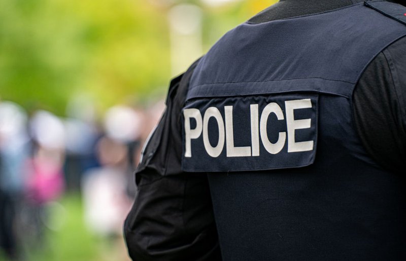 Back view of a police officer in uniform, illustrating situations where officer testimony is material at trial, Charter hearings, or evidentiary proceedings in Ontario courts.