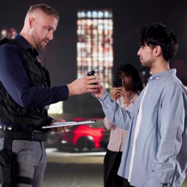 Police officer administering a roadside breath test during an Ontario traffic stop, illustrating mandatory alcohol screening and the legal requirement to comply.