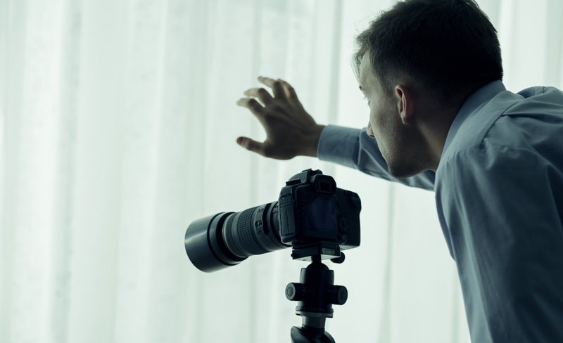 A person using a camera to illustrate surreptitious observation and evidence issues in voyeurism investigations