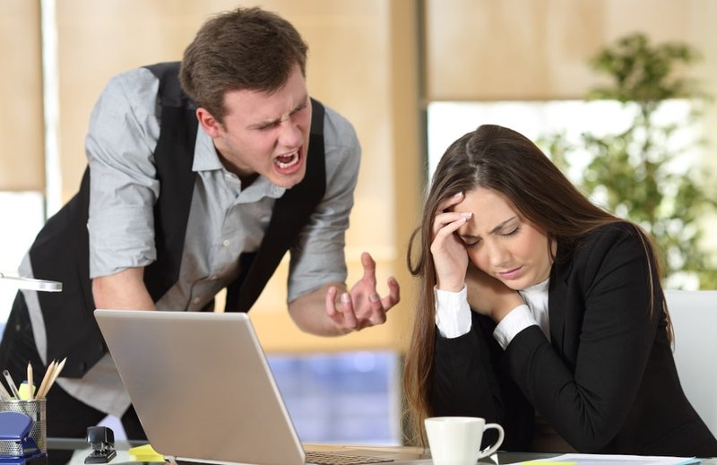 A manager shouting at an employee during a workplace conflict, illustrating how verbal threats can lead to criminal charges in Canada